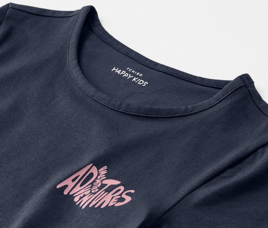 Gros plan sur un t-shirt bleu pour enfant avec l'inscription « Adventures ». 