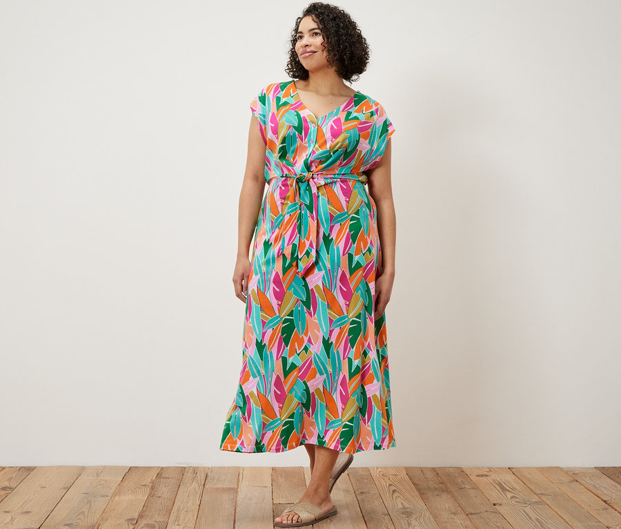 Une femme debout portant une robe en jersey avec nœud.