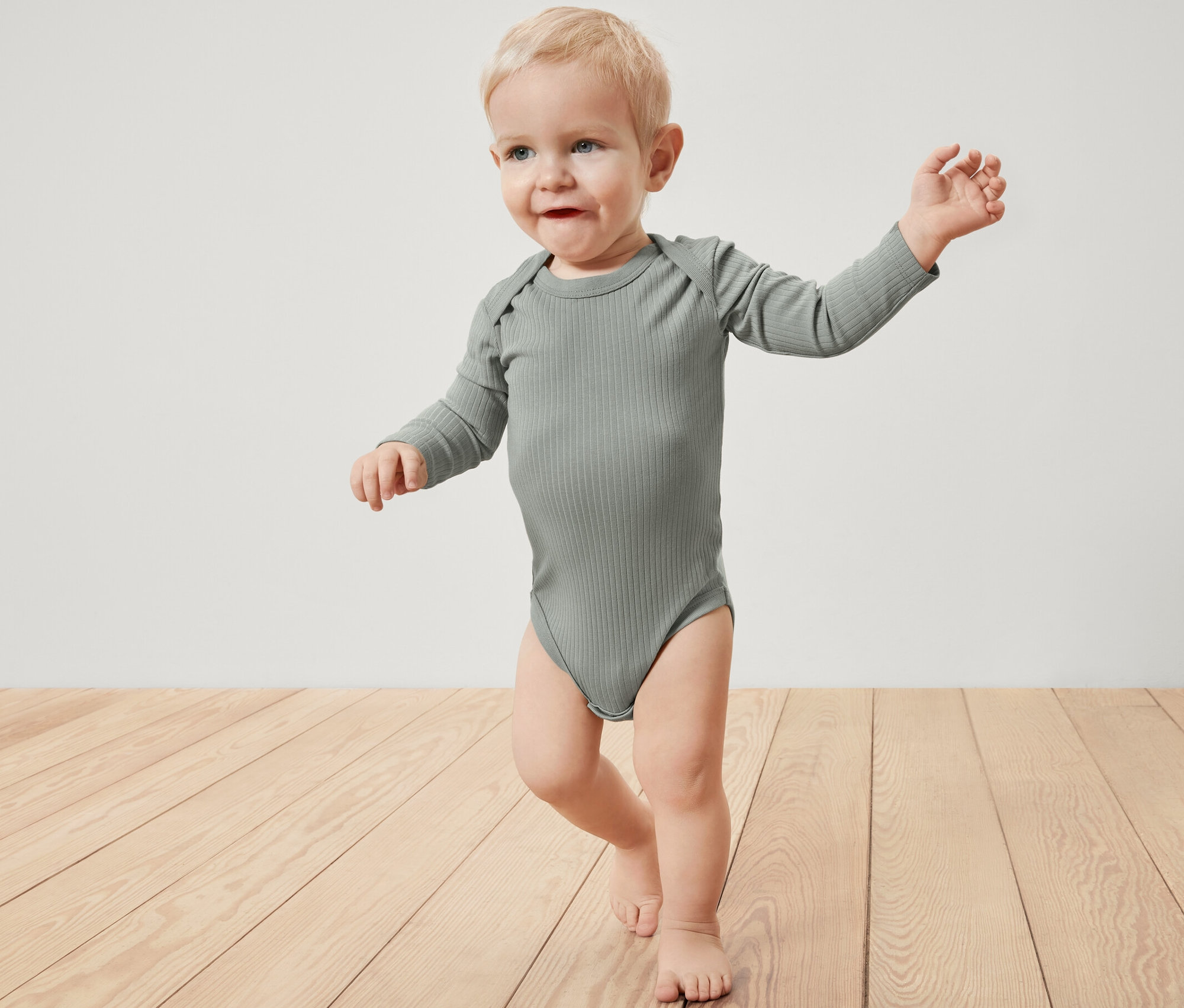 Un bébé porte un body côtelé à manches longues.