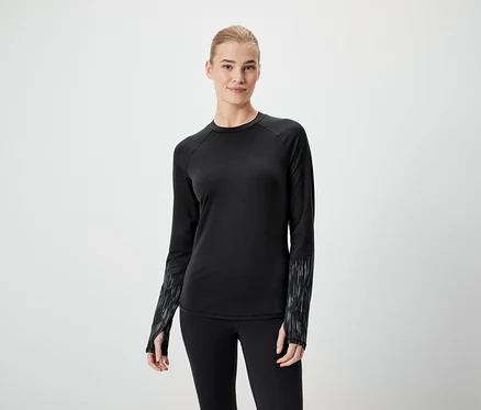 Une femme porte un t-shirt noir à manches longues et un legging noir.