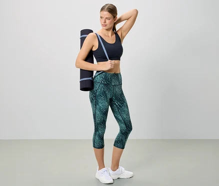 Femme en tenue de sport avec un tapis de yoga sur l'épaule.