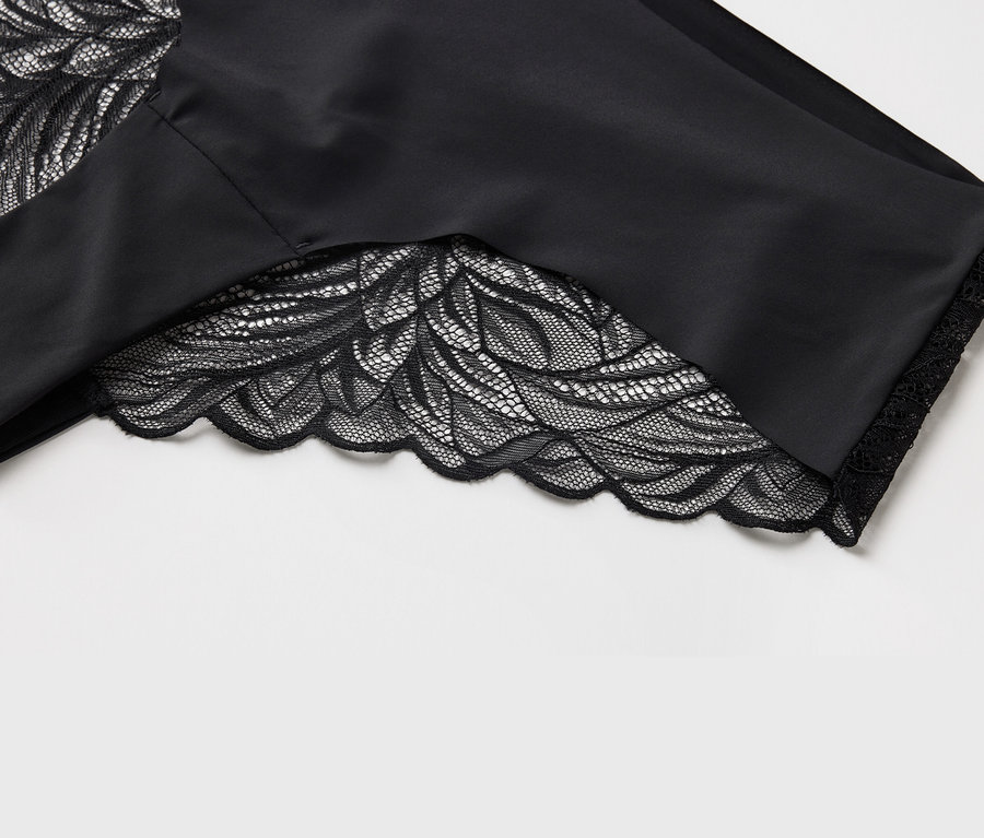 Vue détaillée d'un tissu noir avec de la dentelle florale sur l'ourlet.