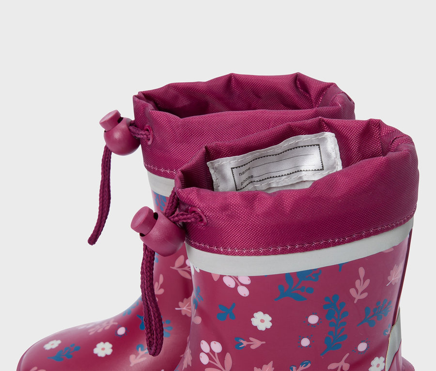 Gros plan sur deux bottes en caoutchouc roses à motifs floraux avec cordon de serrage sur la tige.