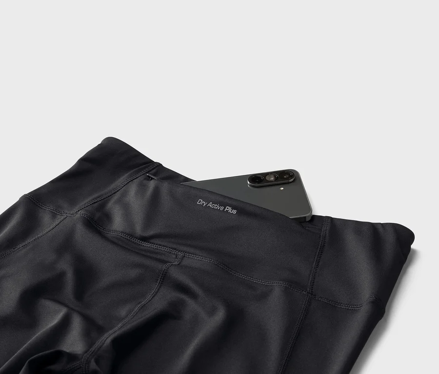 Legging noir avec l'inscription « Dry Active Plus » et un smartphone dans la poche arrière.