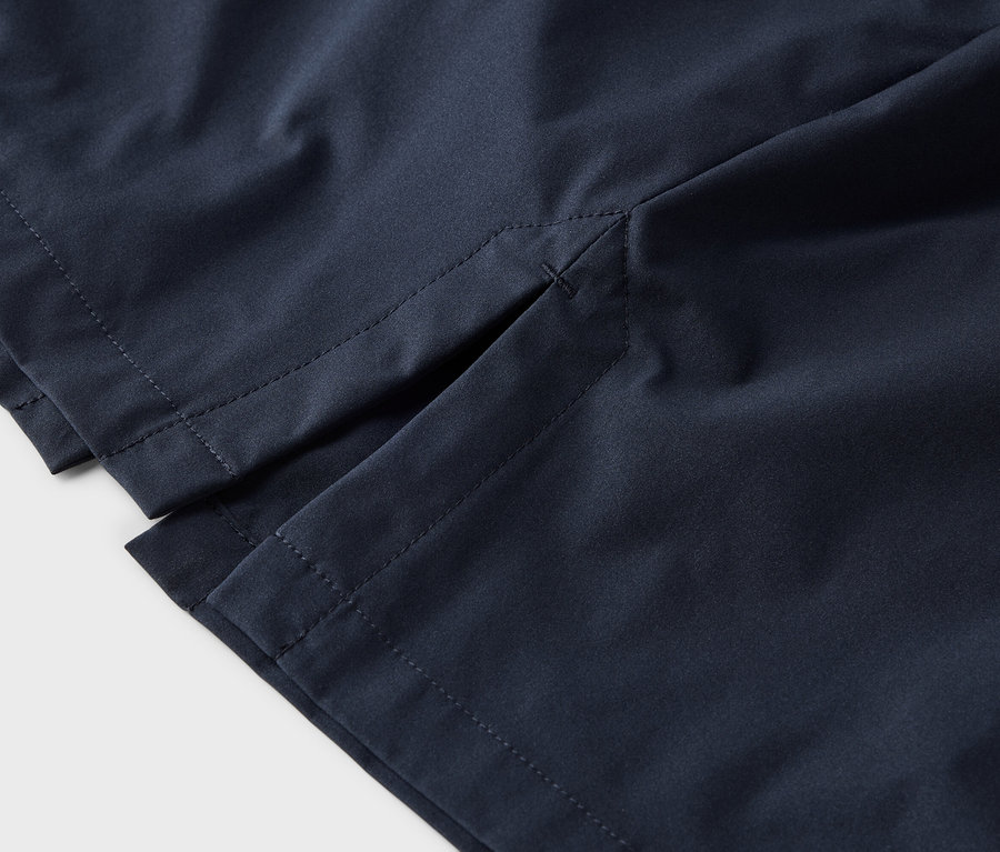 Gros plan sur un short bleu marine avec une fente latérale et des coutures grises sur un fond blanc.