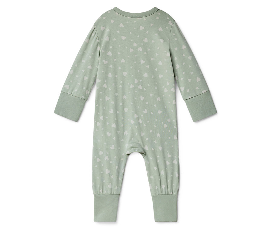 Une grenouillère vert clair à manches longues avec un motif de cœurs blancs posée sur un fond blanc.