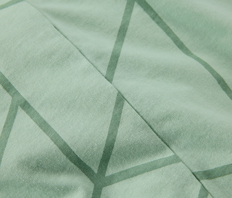 Gros plan d'un tissu vert clair avec un motif géométrique.