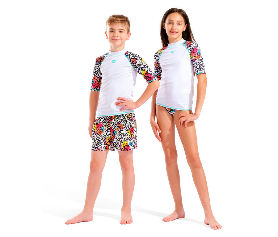 Deux enfants, un garçon et une fille, se tiennent côte à côte devant un fond blanc. Ils portent tous les deux des hauts blancs avec des manches colorées et des bas colorés.