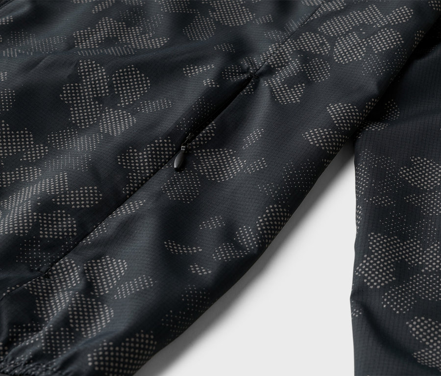 Gros plan d'une veste noire zippée avec un motif de points gris.