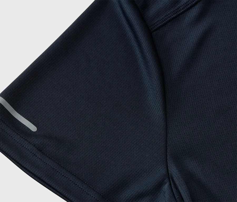 Gros plan d'un t-shirt de sport bleu marine avec une texture en maille et une bande réfléchissante sur la manche.