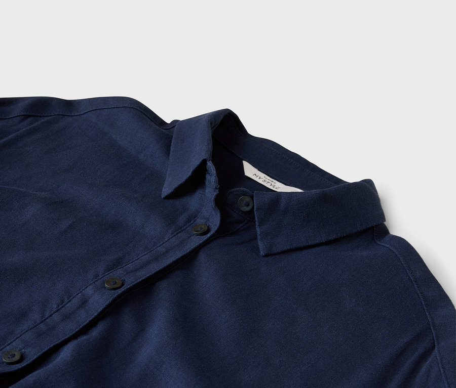 Gros plan d'une chemise bleu foncé avec col et boutons.