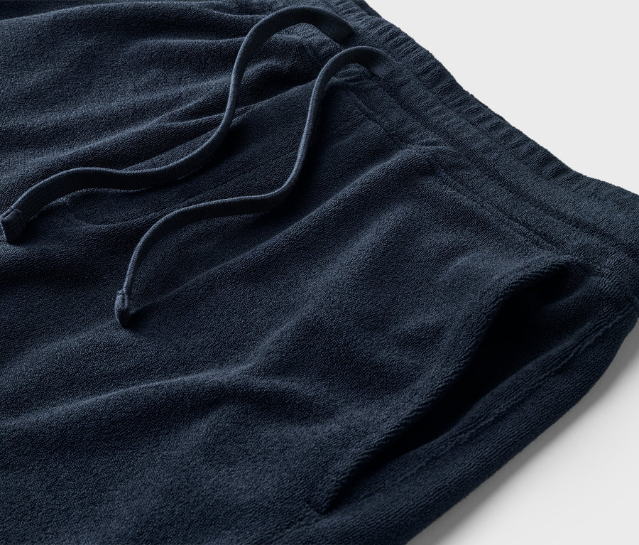 Gros plan d'un short éponge bleu marine avec cordon de serrage et poche.