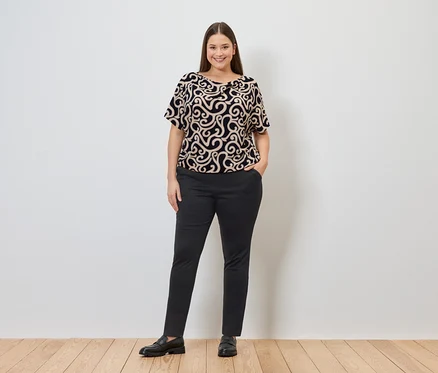 Femme portant un haut à motifs et un pantalon de jogging, une main dans la poche.