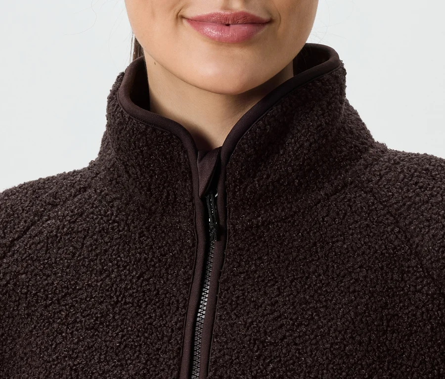 Gros plan d'une femme portant une veste polaire marron zippée à col montant.