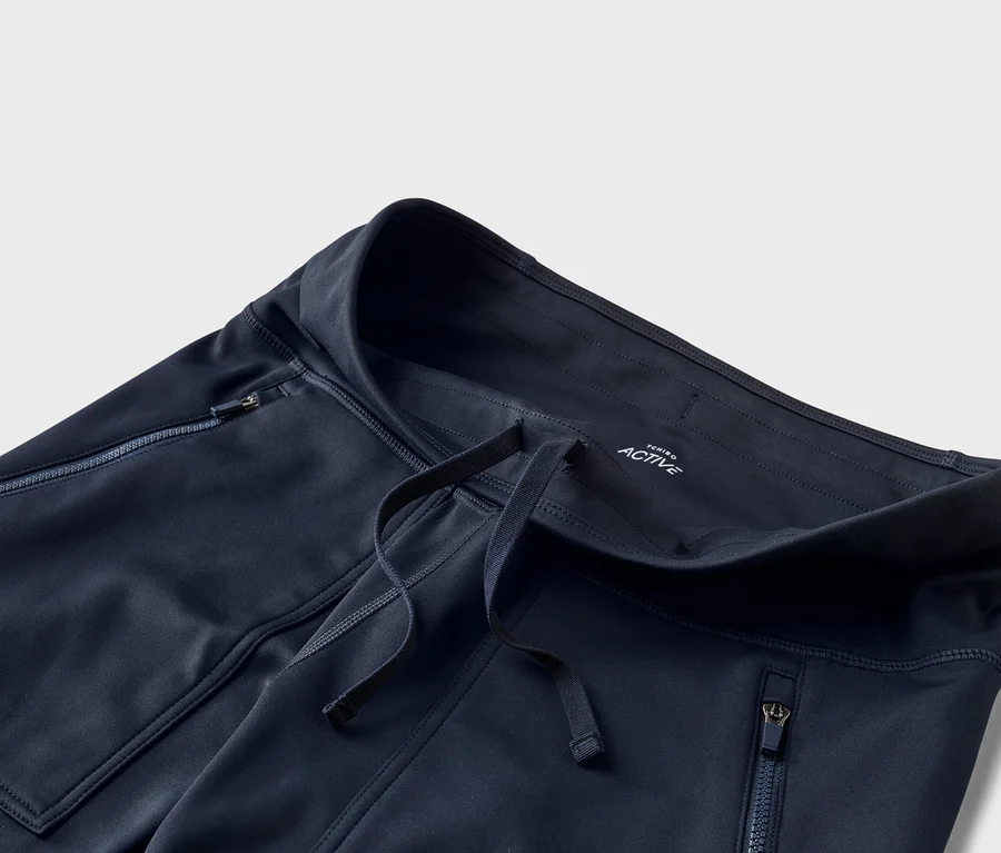 Pantalon de sport bleu marine avec cordon de serrage à la taille et poches latérales zippées. "TCHIBO ACTIVE" est inscrit à l'intérieur de la taille.