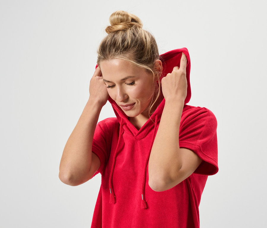 Femme avec un chignon portant un sweat à capuche rouge.