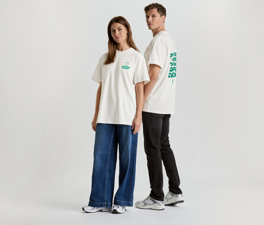 Une femme en jean et un homme en pantalon noir, tous deux portant des t-shirts blancs imprimés.