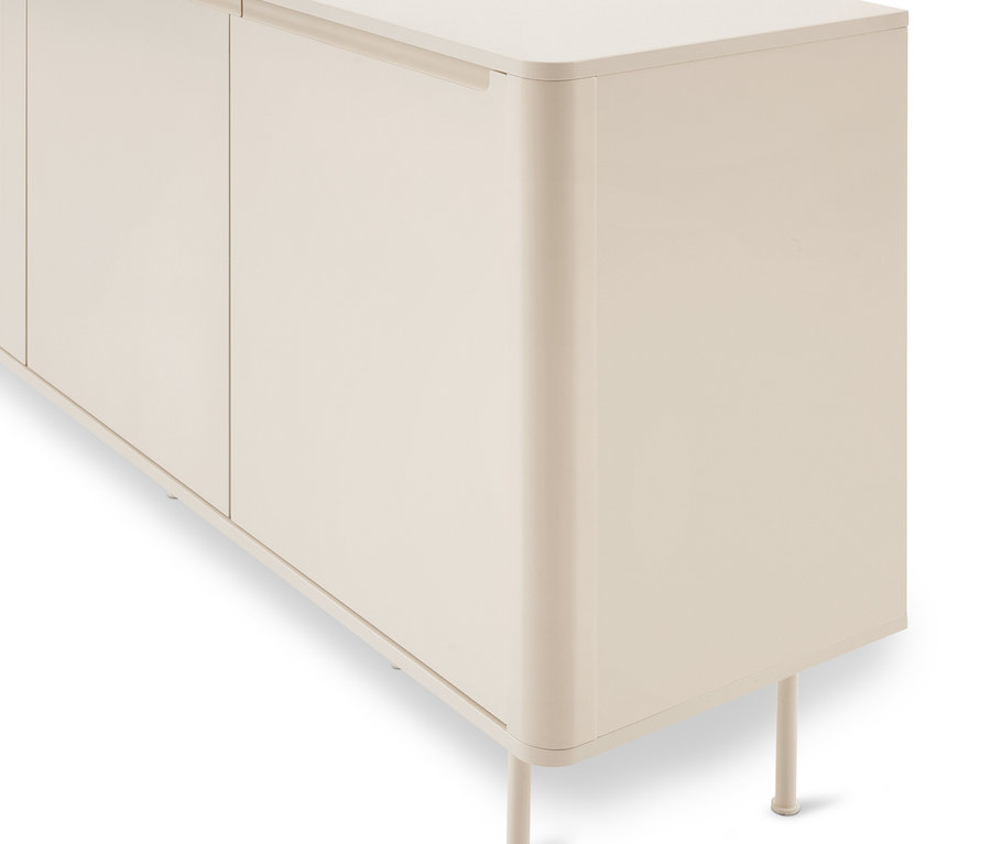 Gros plan d'une armoire beige clair avec des bords verticaux arrondis et des pieds fins. L'armoire a au moins deux portes avec des poignées intégrées et encastrées.