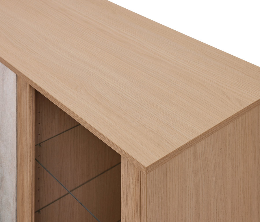 Gros plan d'une armoire en bois clair avec une section ouverte révélant un intérieur sombre et un panneau texturé clair.