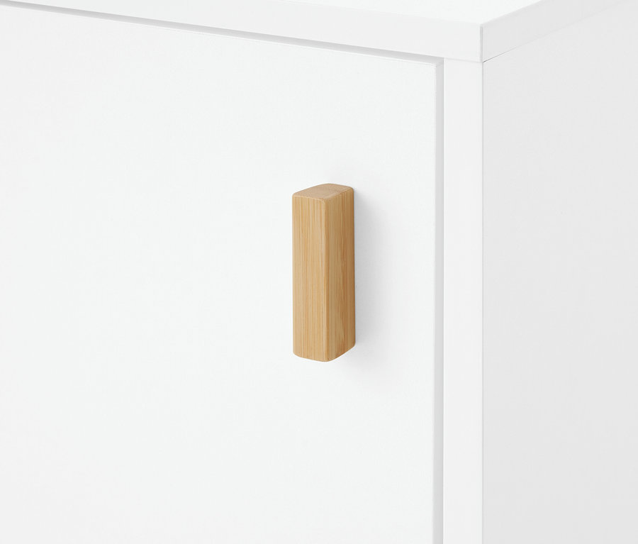 Poignée en bois rectangulaire de couleur claire sur une porte d'armoire blanche.