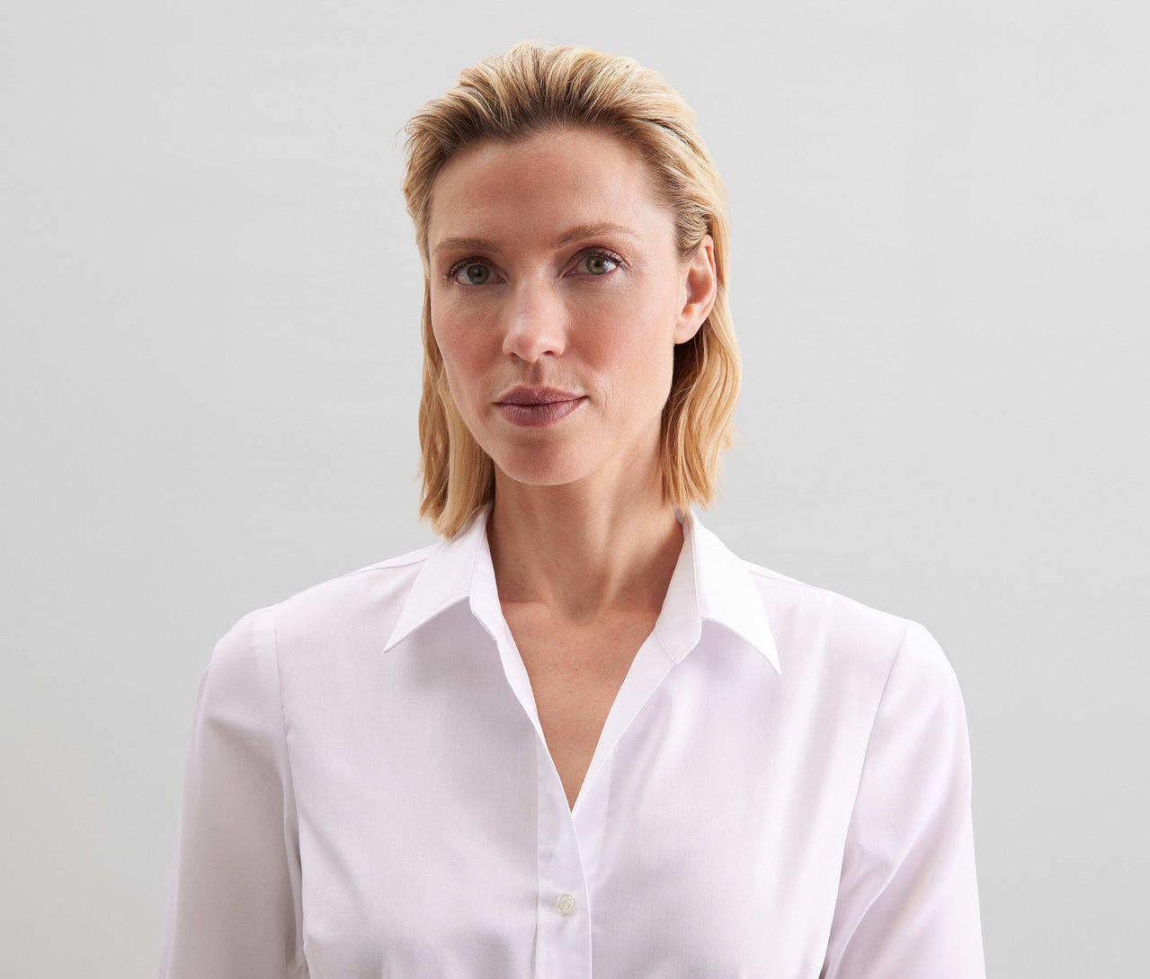 Femme aux cheveux blonds portant un chemisier Slim Fit non iron Seidensticker blanc.