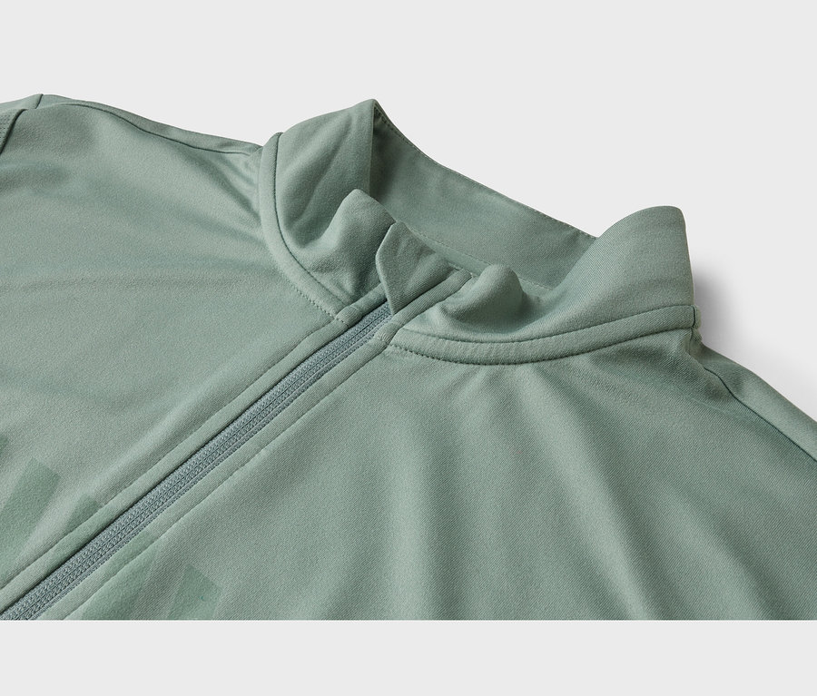 Gros plan d'une veste vert clair avec un col montant et une fermeture éclair mi-longue.