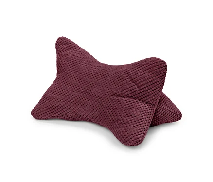 Un coussin bordeaux texturé est posé sur un fond blanc.