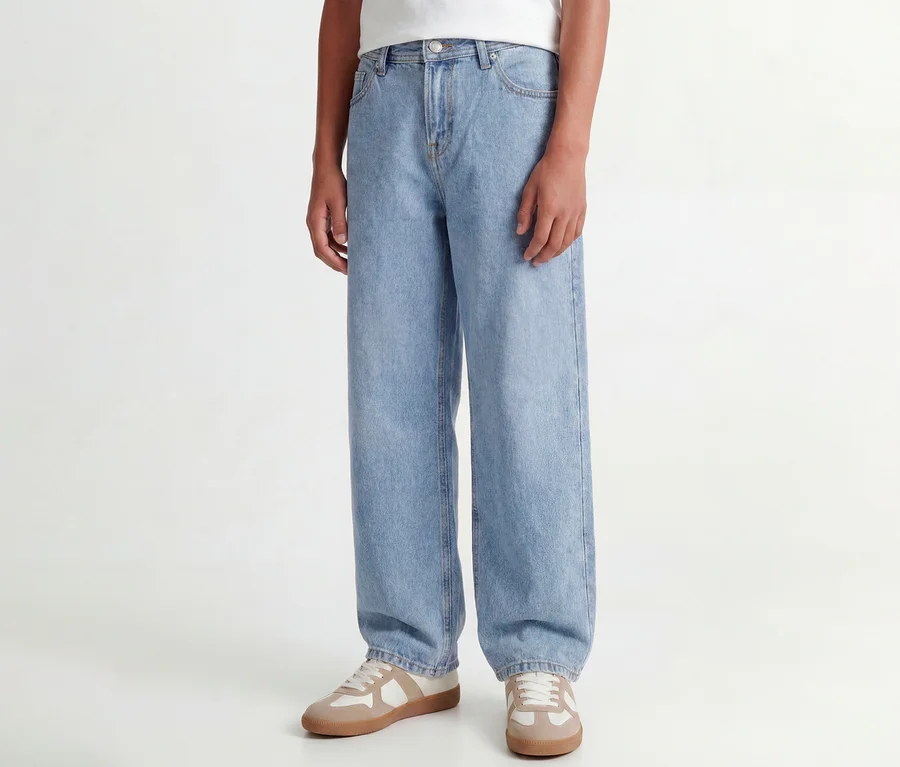 Personne portant un jean Jack&Jones JJOriginal Alex bleu clair et des baskets beige et blanc.