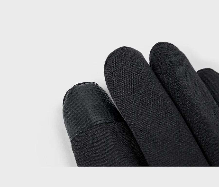 Gros plan de gants en softshell noirs, montrant un bout de doigt texturé et le tissu lisse.