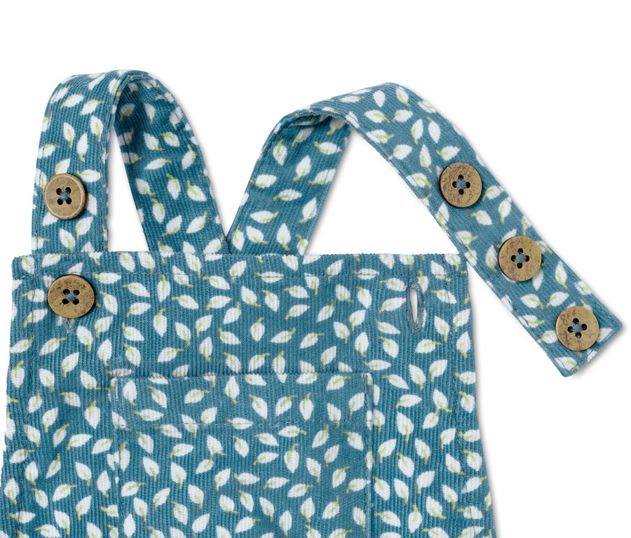 Gros plan sur une grenouillère en velours côtelé bleu avec un motif de feuilles et des boutons.