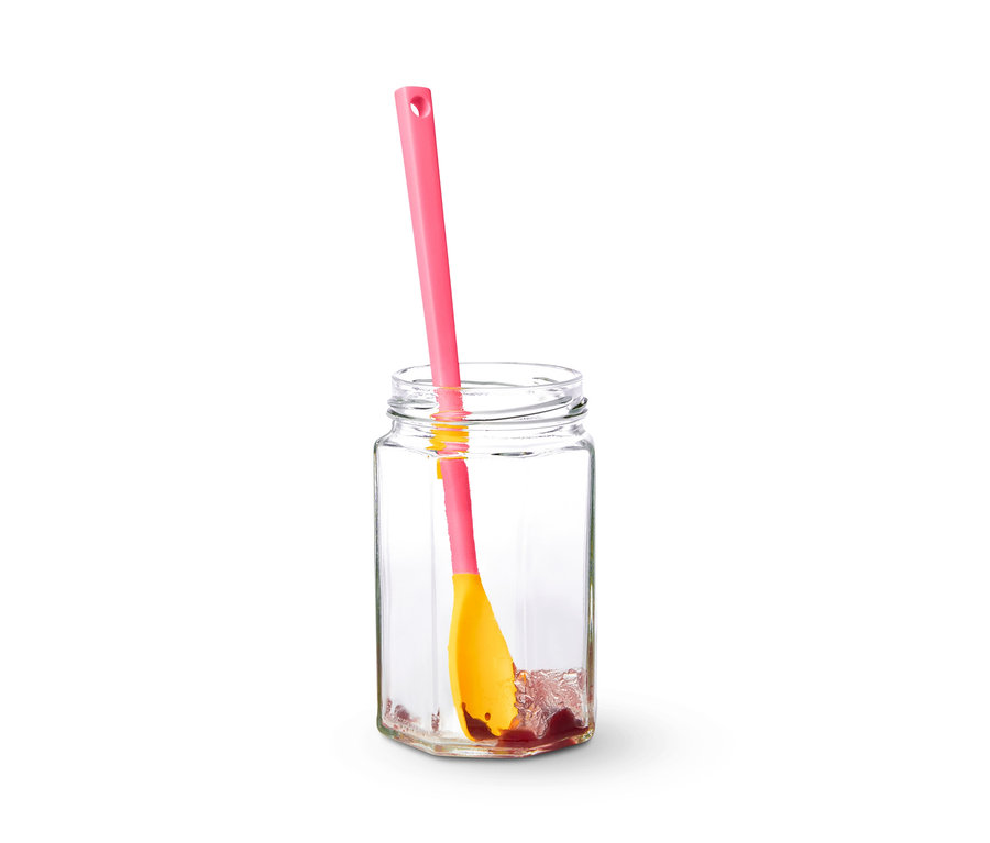 Une cuillère spéciale en silicone est dans un bocal transparent avec de la confiture.