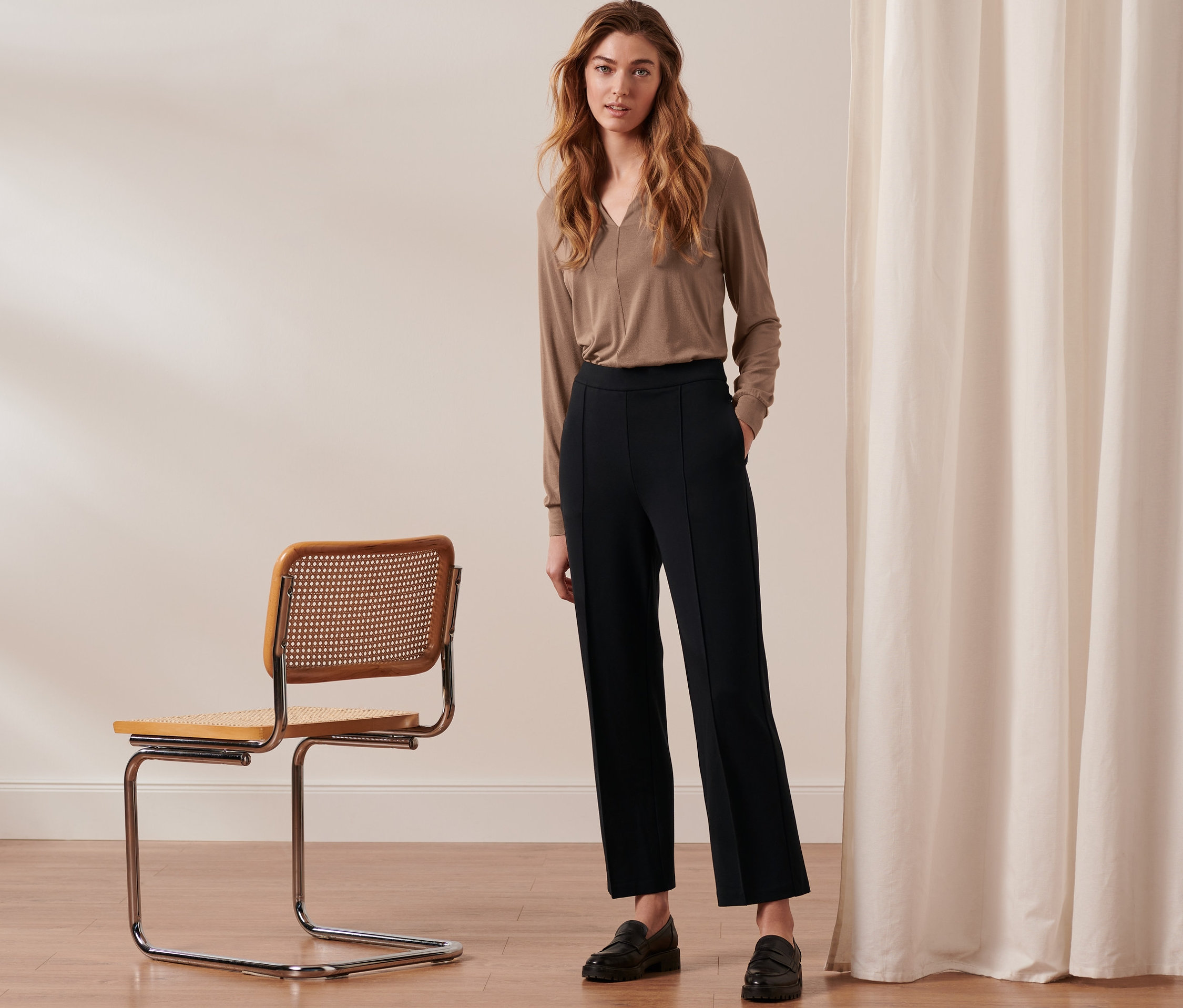 Une femme debout porte un pantalon en jersey noir avec nervure.