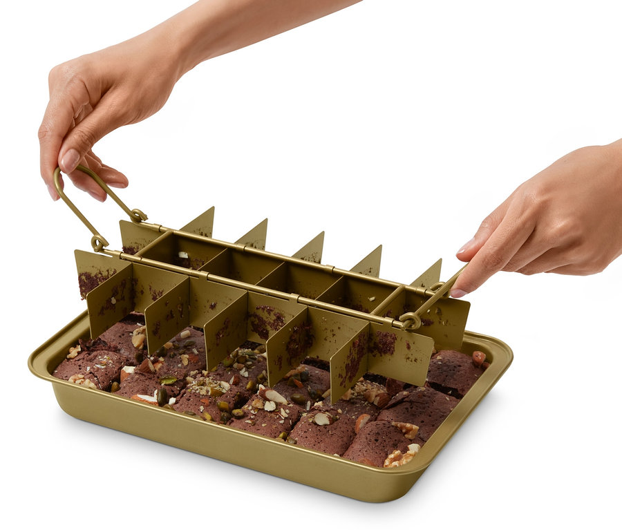 Une personne tient un moule à brownie au-dessus d'une plaque à pâtisserie avec des brownies coupés.