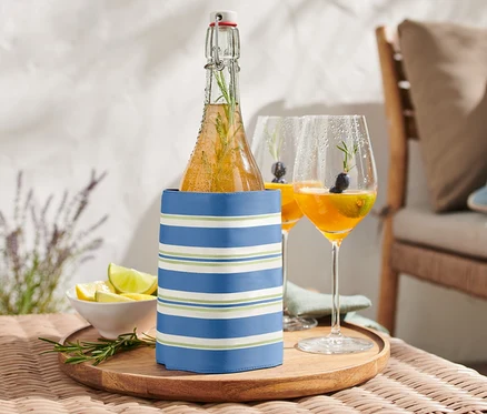 Bouteille dans une manchette de refroidissement sur une table à côté de deux verres de boisson.