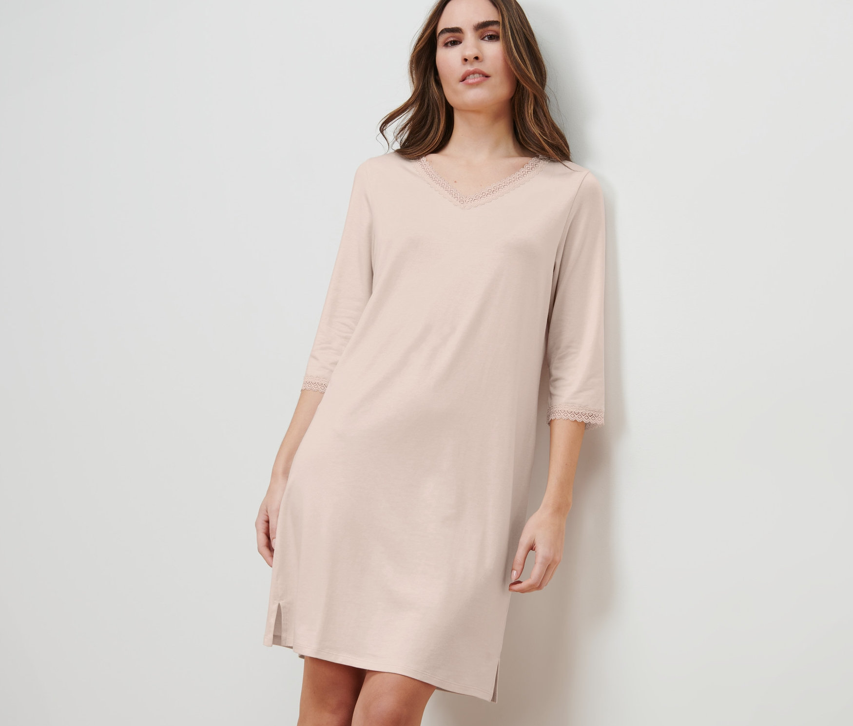 Femme adossée au mur portant une chemise de nuit.