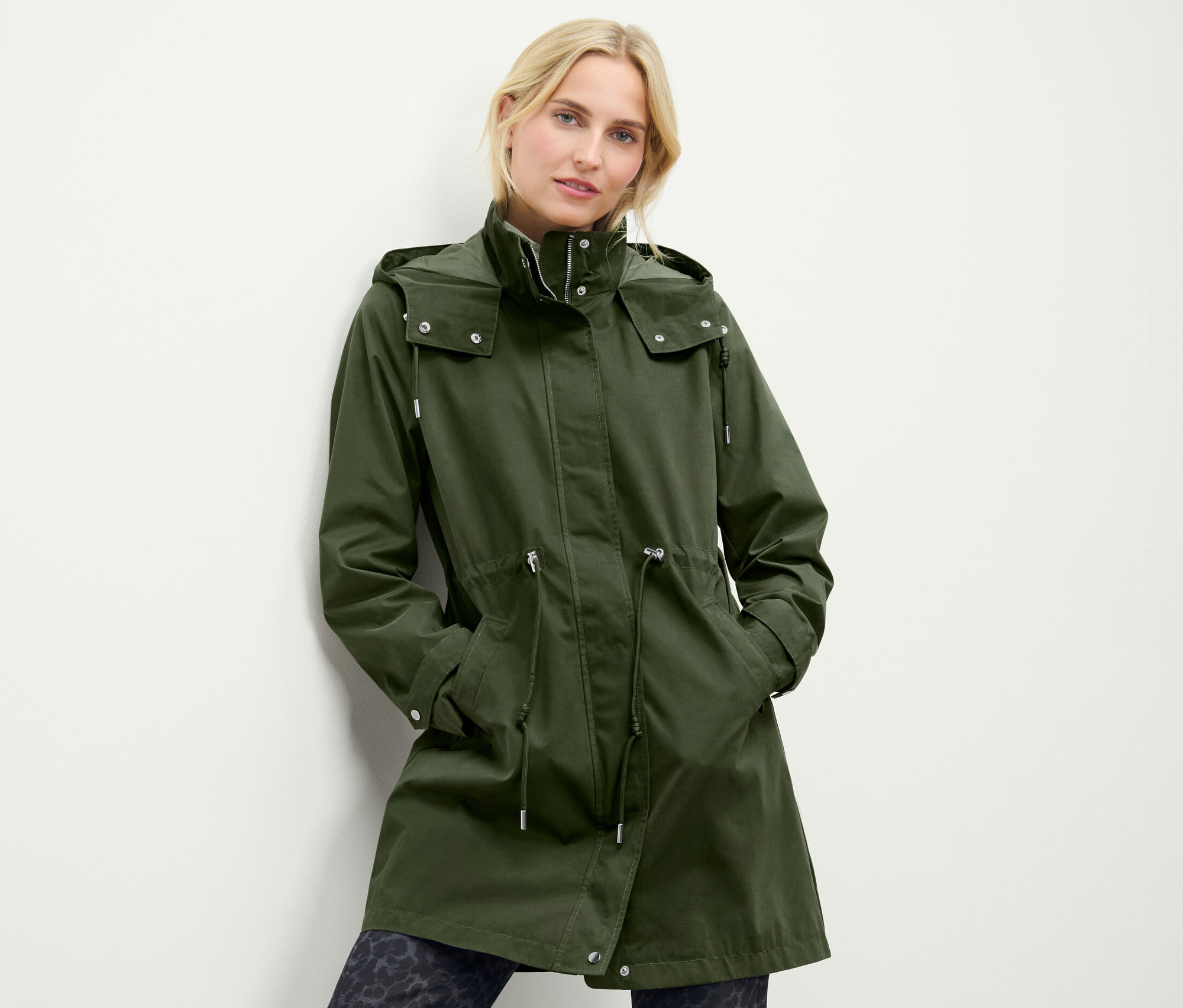 Femme portant une parka à capuche verte.