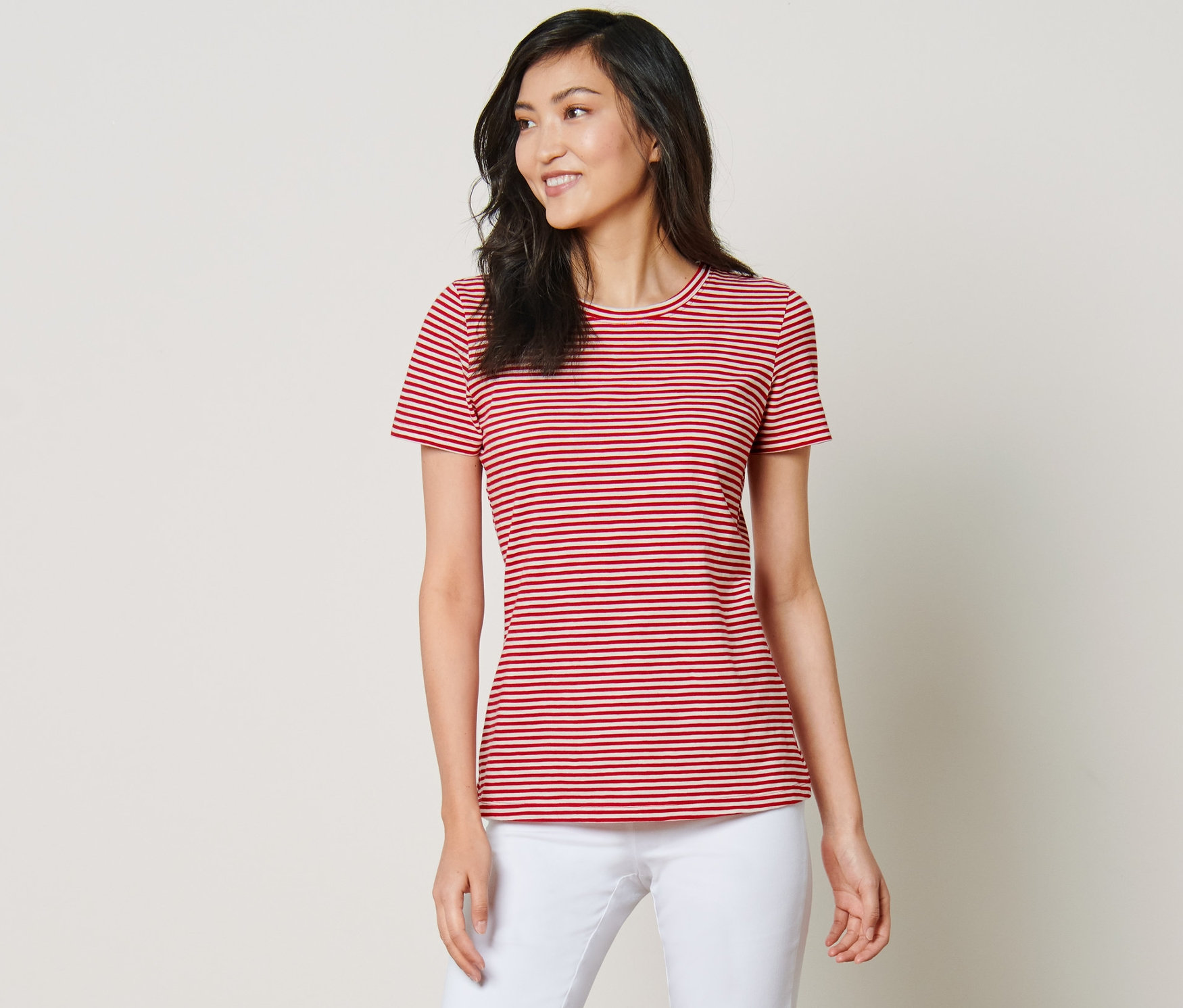 Femme posant en t-shirt à rayures et pantalon blanc.