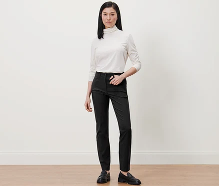 Femme portant un pull à col roulé blanc et un pantalon en bengaline noir.