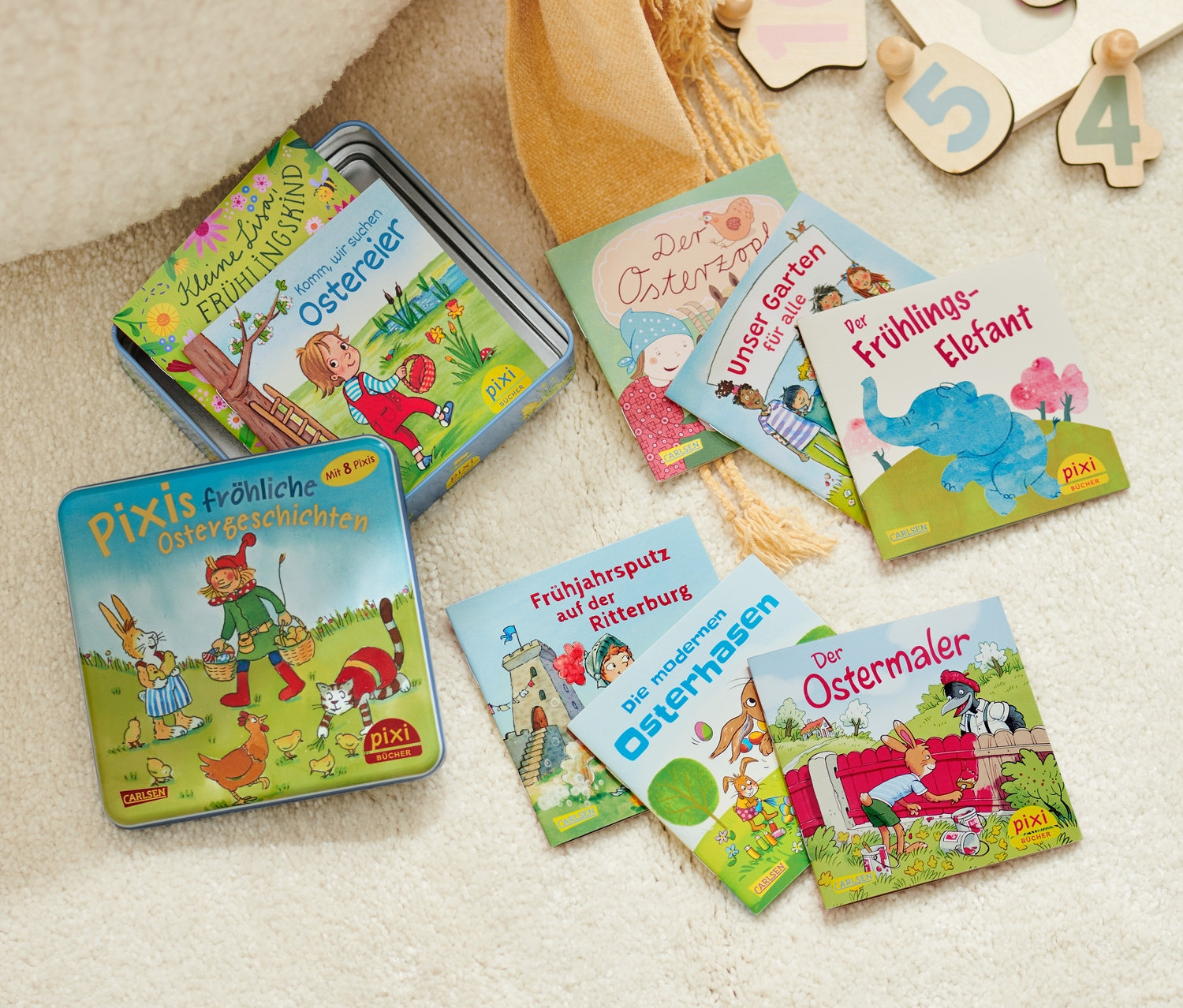 Une boîte métallique de livres Pixi et un puzzle en bois avec des chiffres sont posés sur un tapis shaggy.