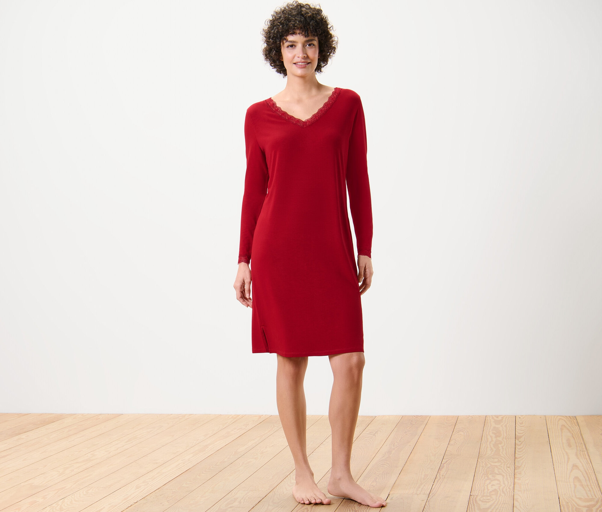 Une femme debout porte une chemise de nuit rouge avec des bordures en dentelle.