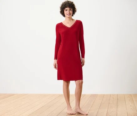 Une femme debout porte une chemise de nuit rouge avec des bordures en dentelle.