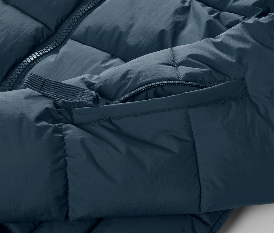 Vue détaillée d'une veste de ski matelassée bleu marine avec fermeture éclair et poche.