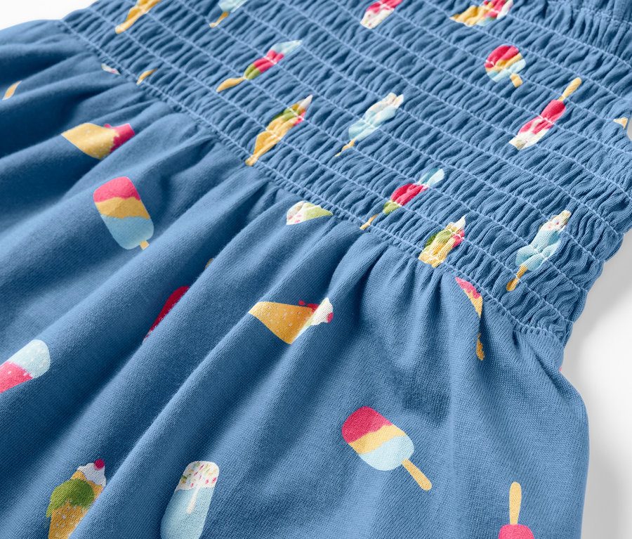 Détail d'une robe à bretelles bleue avec imprimé de glaces.