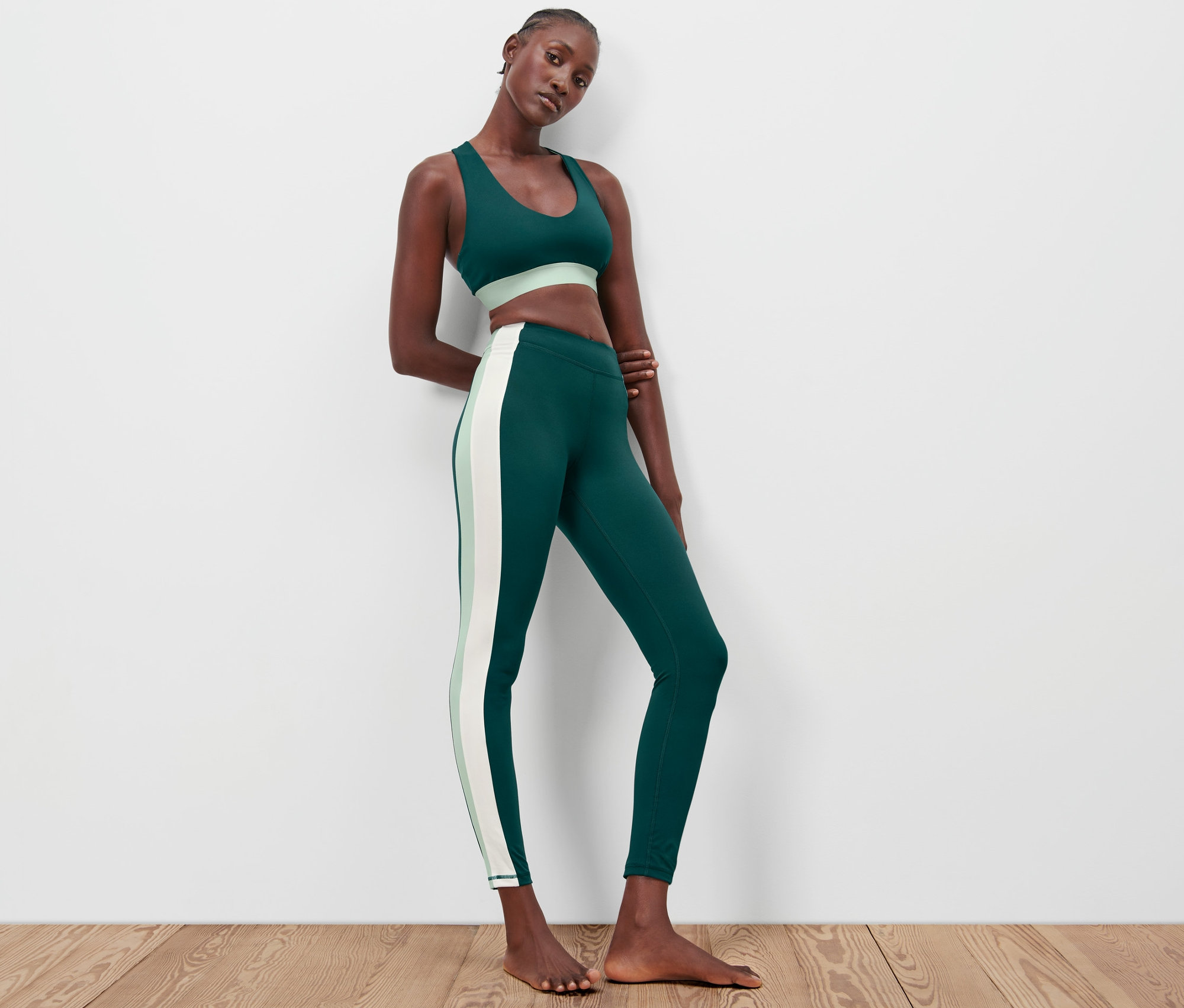 Femme posant en legging de sport vert foncé et soutien-gorge de sport.