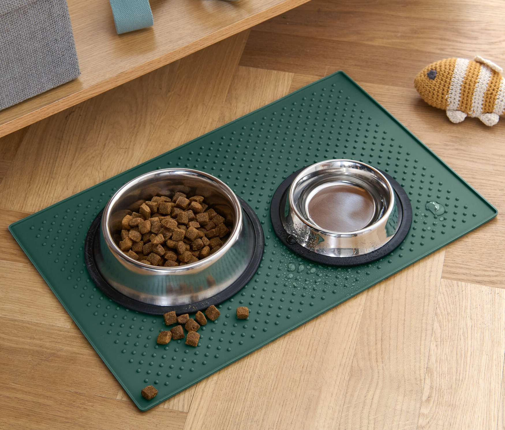 Deux gamelles pour animaux sont posées sur un dessous de gamelle vert sur un plancher en bois.
