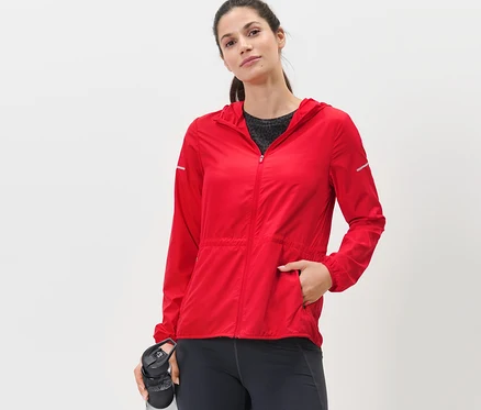 Femme posant en veste de course légère rouge.