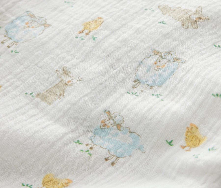 Gros plan sur 3 serviettes en mousseline pour bébé avec des imprimés de moutons, de poussins et de lapins.