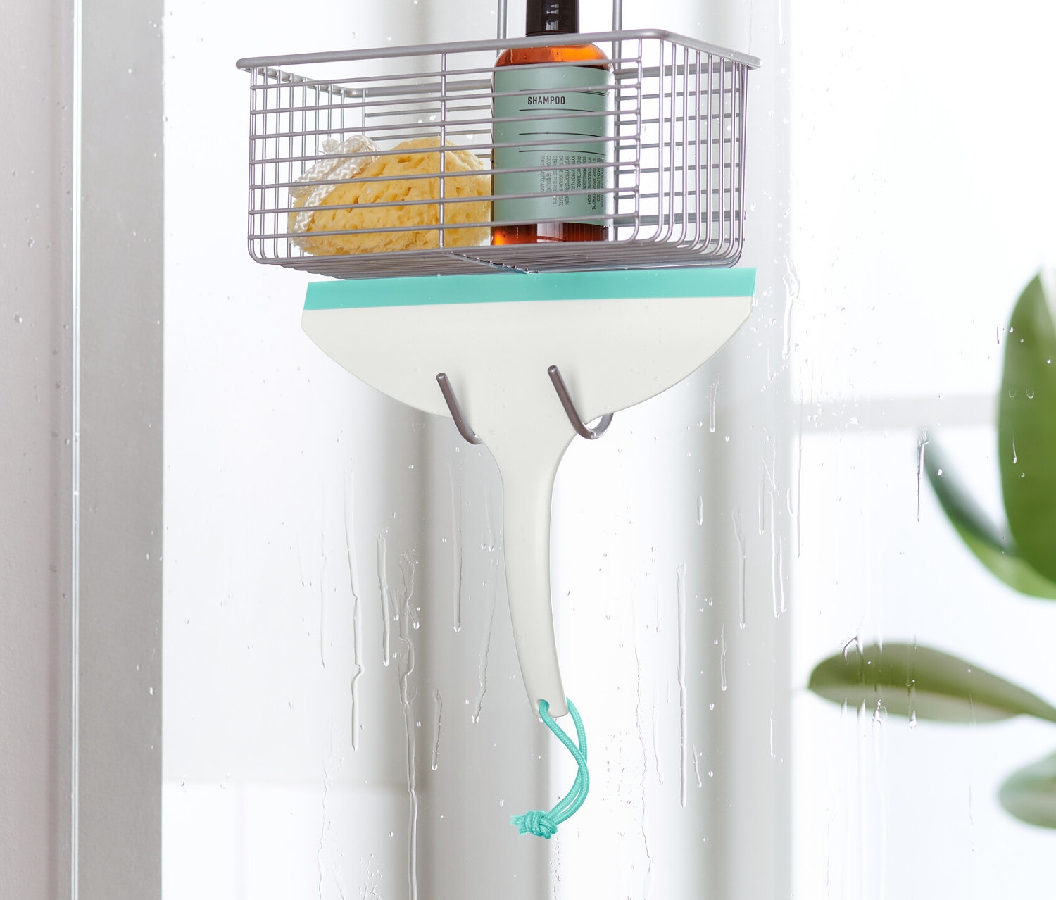 Une raclette pour salle de bain est suspendue à une paroi de douche.