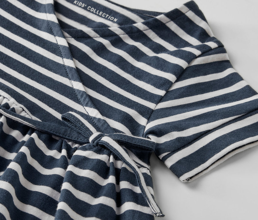 Gros plan sur une robe en jersey pour enfant avec des rayures bleues et blanches et un cordon à la taille.