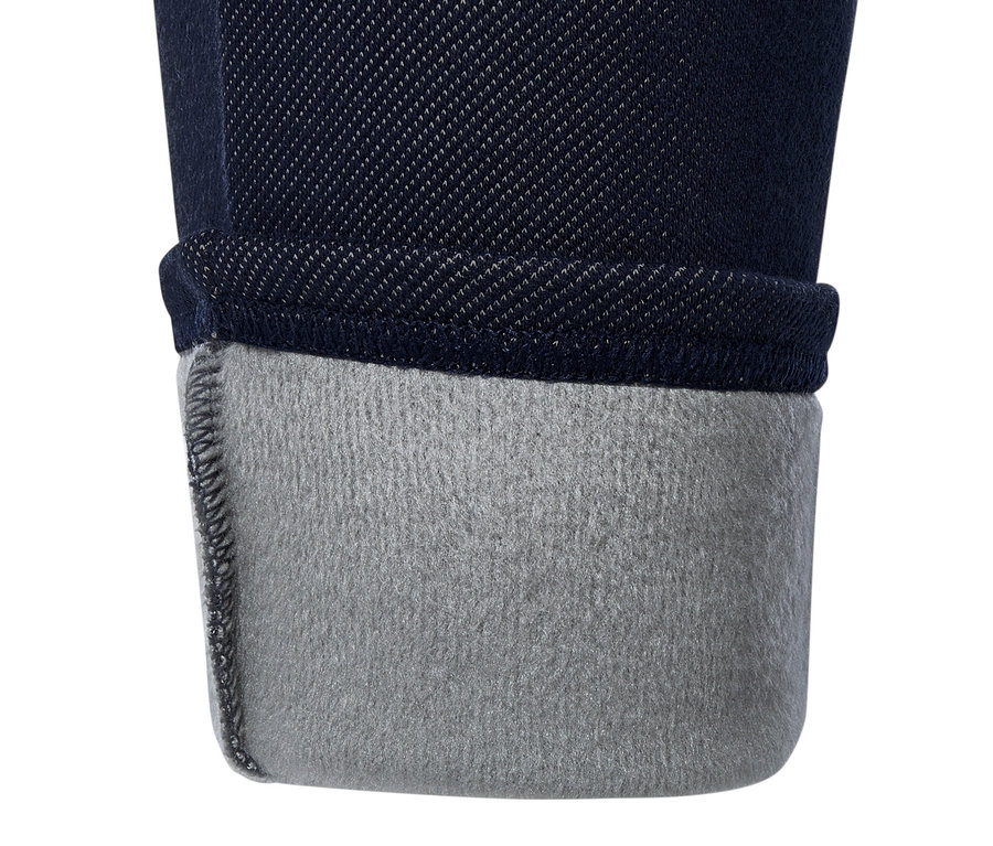 Gros plan sur un legging en jean bleu marine avec un ourlet retroussé révélant une doublure grise.